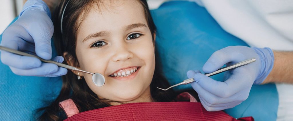 close up portrait of caucasian girl having an examination at the pediatric dentist while smiling at front 1